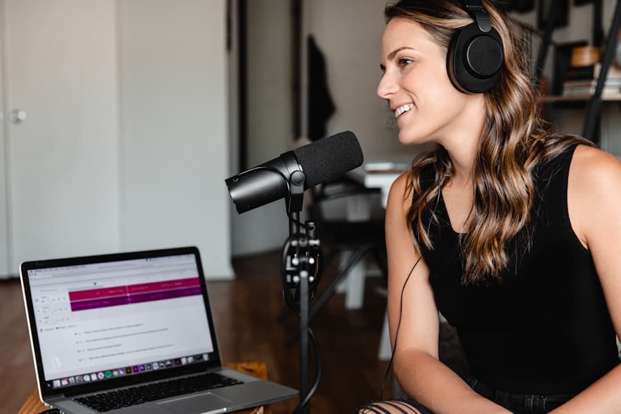 A smiling podcaster with headphones recording at a studio microphone